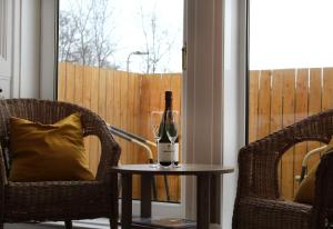 una botella de vino en una mesa junto a dos sillas en The Woodhouse Hotel, en Largs