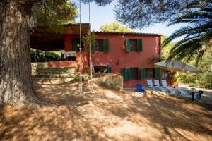 een rood huis met een boom en een schommel bij Casa Nocella a Bagnaia - Goelba in Portoferraio