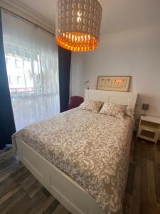 een slaapkamer met een bed en een kroonluchter bij Casa Ana in Sanlúcar de Barrameda