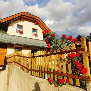 Una casa con una valla con flores rojas. en Al sentiero di Charly, en Tarvisio