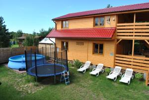 a backyard with a house with a pool and chairs at Skarb Bałtyku in Debina