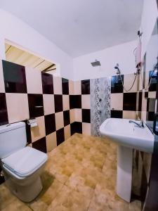 La salle de bains est pourvue de toilettes et d'un lavabo. dans l'établissement Rainforest River Bay, à Deniyaya