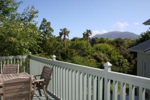 a white fence with two chairs and a table at Constantia cottage- Warblers Nest in Cape Town
