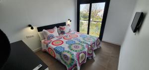 sypialnia z łóżkiem z kolorową kołdrą i oknem w obiekcie JOSE APARTAMENTo w mieście San Jose de la Rinconada