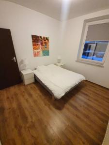 a bedroom with a white bed and a wooden floor at Apartament żeglarski Węgorzewo in Węgorzewo