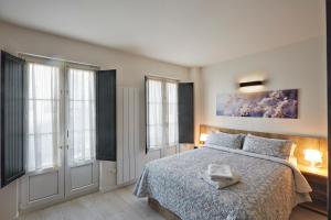 a bedroom with a bed with a blue blanket and windows at Apartamentos Abastos in Logroño