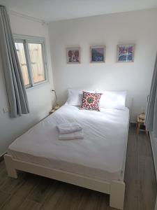 a bedroom with a white bed with a pillow on it at חאן בכפר במשק בלה מאיה - הצימר in Nevatim