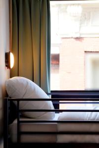 a bed with a pillow in front of a window at Pink Flamingo Boutique Hostel in The Hague