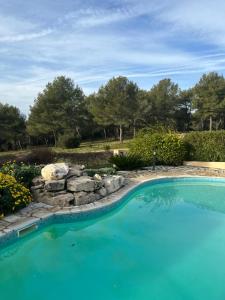 Una piscina en un patio con un muro de contención de piedra y árboles. en Au Petit Paradis, en Roquefort-la-Bédoule