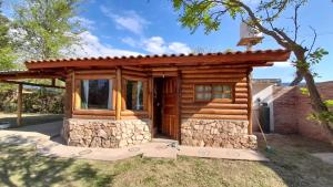 a small log cabin with a stone wall at Hotel y Cabañas Green Park in Nono