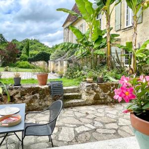 a patio with a table and chairs and plants at Le Tilleul in Grézillac