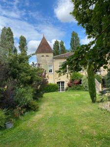 ein Haus mit einem Hof mit Gras und Bäumen in der Unterkunft Le Tilleul in Grézillac