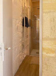 uma casa de banho com uma cabina de duche ao nível do chão ao lado de uma parede de pedra em Le Tilleul em Grézillac