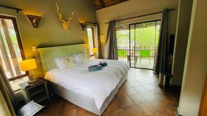 1 dormitorio con 1 cama grande con colcha blanca en Ujabule Lodge en Hoedspruit