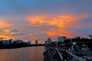 a view of a river with a city at sunset at Hotel Gulshan Lake View in Dhaka