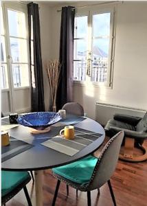 een eetkamer met een tafel, stoelen en ramen bij Apartment balcon & parking in Serris