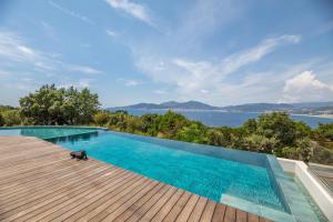 a swimming pool on a deck with a view of the water at Domain U Tempu Persu landscaped parc mini zoo in Porticcio