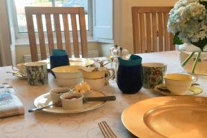 una mesa con platos y tazas y un jarrón con flores en Grange Farm, en Thetford