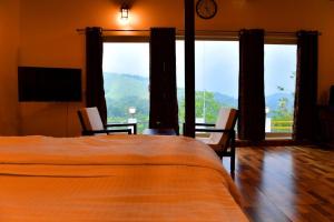 a bedroom with a bed and two chairs and a television at Heaven Valley Resorts Vagamon in Vagamon