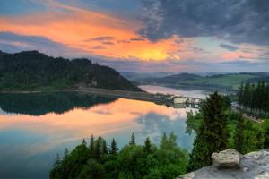 um comboio numa ponte sobre um lago ao pôr-do-sol em Pod Wdżarem em Kluszkowce