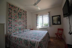 a bedroom with a bed with a floral headboard and a window at Le Case Rosa vicino Tropea in Santa Domenica