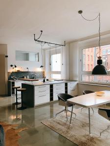 uma cozinha com armários brancos e uma mesa e cadeiras em GOHO Loft em Nurembergue