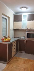 Vrnjačka BanjaにあるApartman Nikola- 4 ZVEZDICE minimalno 3 nocenja za rezervacijuのキッチン(茶色のキャビネット付)、カウンターにフルーツを用意しています。 +6枚の写真