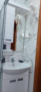 a white bathroom with a sink and a mirror at Vila MINA in Bajina Bašta