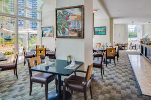 uma sala de jantar com mesas, cadeiras e janelas em 1 Bedroom Suite at GalleryOne condo em Fort Lauderdale