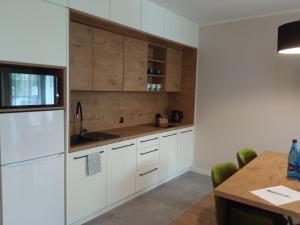 a kitchen with white cabinets and a wooden table at Apartamenty Woda i Las in Turawa +31 photos