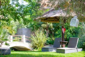 a garden with two chairs and an umbrella and a bridge at Achtis Hotel in Afitos