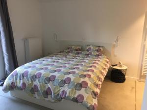 ein Bett mit farbenfroher Bettdecke in einem Schlafzimmer in der Unterkunft Le temps d’une balade. in Olne