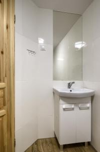 a white bathroom with a sink and a mirror at Chata Litwor in Bukowina Tatrzańska