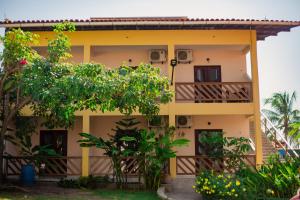 ein gelbes Haus mit einem Balkon und Bäumen in der Unterkunft Pousada D' Areia in Barreirinhas