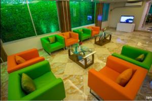 een woonkamer met oranje en groene stoelen en een televisie bij Hotel Gulshan Lake View in Dhaka