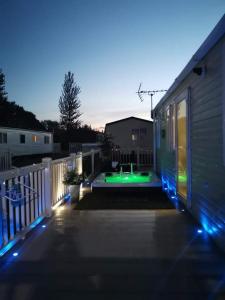 un patio trasero con piscina y una casa con luces en Static Caravan with hot tub, en Tattershall
