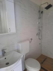 La salle de bains blanche est pourvue de toilettes et d'un lavabo. dans l'établissement Apartmani Aleksandar, à Nevesinje