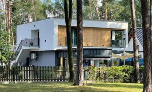 a white house with a fence and some trees at Apartamenty Woda i Las in Turawa