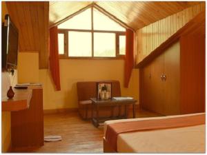 Habitación con cama, mesa y ventana en Hotel Greenfields, en Manali