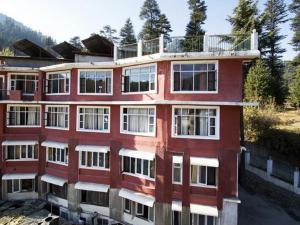 a red building with a balcony on top of it at Hotel Greenfields in Manāli