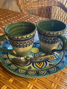 duas chávenas e colheres num prato numa mesa em Писанка Плюс em Yaremche