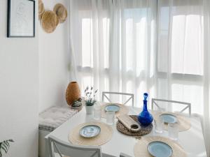 a white table with chairs and blue plates on it at Apartament Ampolla Port in L'Ampolla
