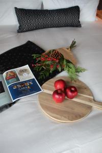 eine Holzplatte mit Äpfeln und ein Buch auf einem Bett in der Unterkunft The Larix Hotel in Kimberley
