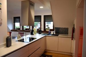 a kitchen with white cabinets and a sink and windows at Bommecke am AquaMagis in Plettenberg