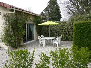 einen Tisch und Stühle mit Sonnenschirm in einem Garten in der Unterkunft Gîte berneval le grand in Berneval-le-Grand