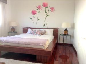 1 dormitorio con 1 cama con flores rosas en la pared en myninho, en Vila Nova de Gaia