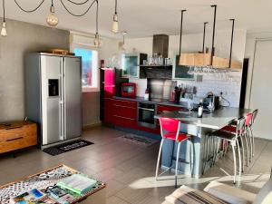 una cocina con nevera de acero inoxidable y armarios rojos en Terrasse sur les Alpilles, en Saint-Rémy-de-Provence