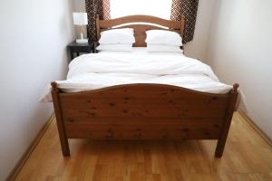 1 dormitorio con cama de madera con sábanas y almohadas blancas en Cosy and Comfortable Apartment in Cracov, en Cracovia