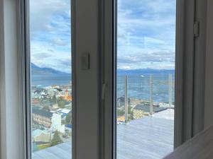 a window with a view of a city and the ocean at Infinity View Pent House III in Ushuaia