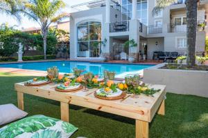 una mesa con comida delante de una piscina en Valdior Guest House, en Durban